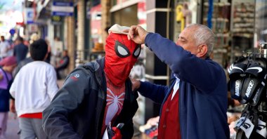 A local shopkeeper places his hat on Ayaz Koç, dressed as Spider-Man, Osmaniye, southern Türkiye, March 30, 2024. (AA Photo)
