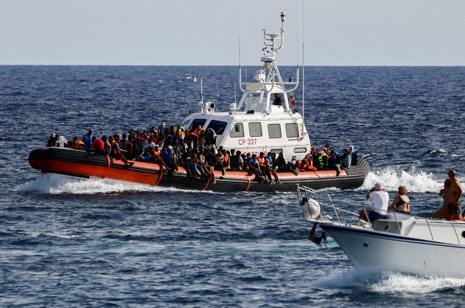 An Italian Coast Guard vessel carrying migrants rescued at sea passes near a tourist boat, Lampedusa, Italy, Sept. 18, 2023. (Reuters Photo)