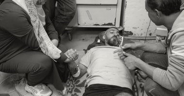A grayscale picture of Palestinian journalist Sami Shehada (C), wounded in an Israeli strike, lying on the floor at Al-Aqsa Hospital, Deir Al-Balah, Gaza Strip, Palestine, April 12, 2024. (Reuters Photo)