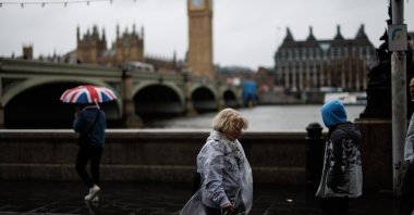 People walk along the Southbank against strong winds in the rain with the Palace of Westminster, home to the Houses of Parliament, in the background, London, Britain, March 28, 2024. (EPA Photo)