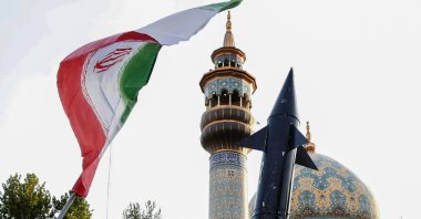 Iranian lift up a flag and the mock up of a missile during a celebration following Iran's missiles and drones attack on Israel, at Palestine square in central Tehran, Iran, April 15, 2024. (AFP Photo)