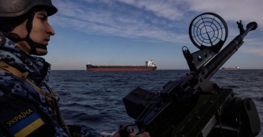 A member of Ukraine's coast guard mans a gun on a patrol boat as a cargo ship passes by in the Black Sea, amid Russia’s attack on Ukraine, Feb. 7, 2024. (Reuters Photo)