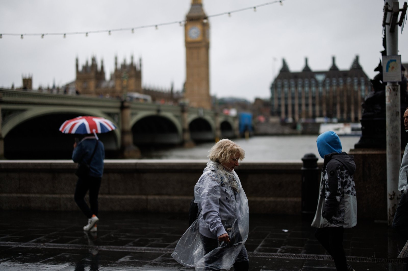 People walk along the Southbank against strong winds in the rain with the Palace of Westminster, home to the Houses of Parliament, in the background, London, Britain, March 28, 2024. (EPA Photo)