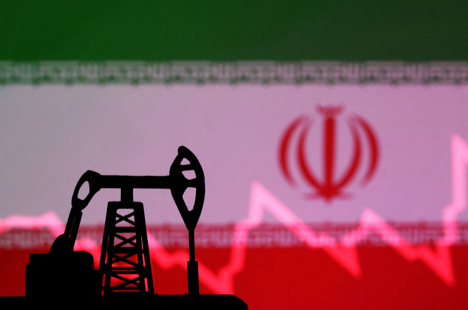 Iranian flag with stock graph and an oil pump jack miniature model are seen in this illustration taken Oct. 9, 2023. (Reuters Photo)