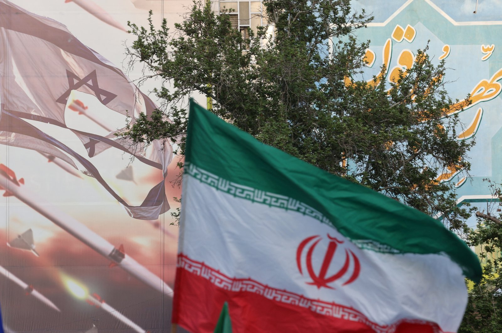 An anti-Israel billboard is seen next to the Iranian flag during a celebration following Iran&#039;s Revolutionary Guard Corps (RGC) attack on Israel, in Tehran, Iran, April 15, 2024. (Reuters Photo)