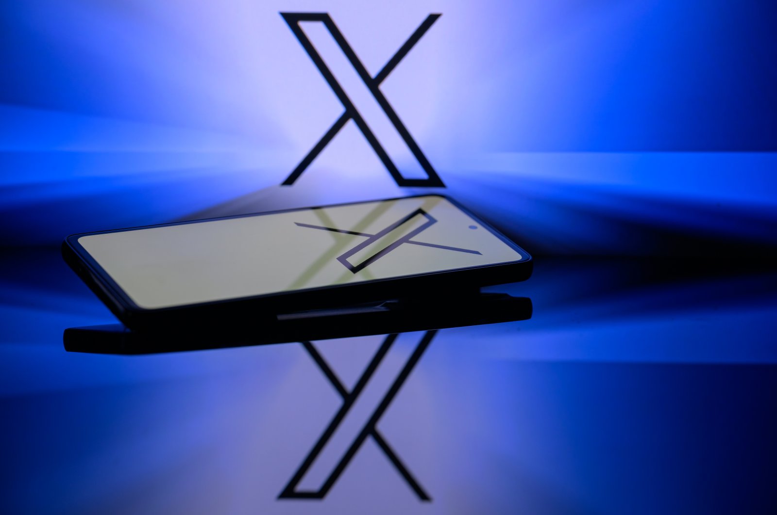The X logo is displayed on a smartphone, with the X app, formerly known as Twitter, and X visible in the background, in this photo illustration taken in Brussels, Belgium, Jan. 5, 2024. (Reuters Photo)