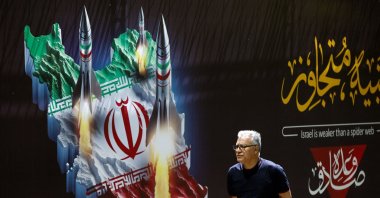 A man walks past a banner depicting missiles along a street, Tehran, Iran, April 19, 2024. (AFP Photo)