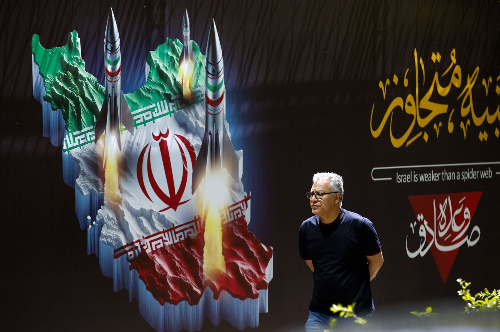 A man walks past a banner depicting missiles along a street, Tehran, Iran, April 19, 2024. (AFP Photo)