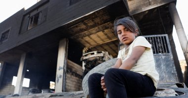 A Palestinian girl sits in front of her house after Israeli settlers attacked the village of al-Mughayyer, Israeli-occupied West Bank, Palestine, April 17, 2024. (Reuters Photo)