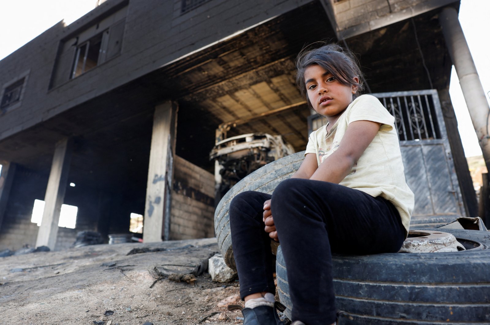 A Palestinian girl sits in front of her house after Israeli settlers attacked the village of al-Mughayyer, Israeli-occupied West Bank, Palestine, April 17, 2024. (Reuters Photo)