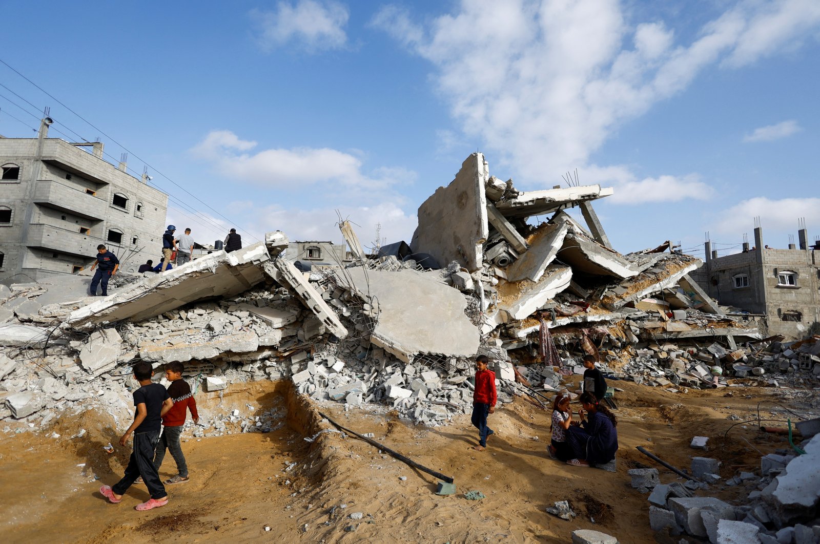 Children walk past as Palestinians inspect the site of an Israeli strike on a house, in Rafah, in the southern Gaza Strip, Palestine, April 21, 2024. (Reuters Photo)