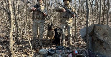 Two soldiers stand guard over materials seized in a PKK hideout in eastern Bingöl province, Türkiye, March 5, 2024. (IHA Photo)