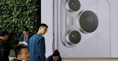 People stand near a screen showing the new Huawei Pura 70 series smartphone as the series models go on sale at Huawei's flagship store, Beijing, China, April 18, 2024. (Reuters Photo)
