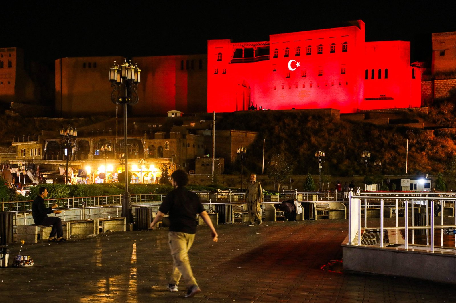 People walk along a path near the citadel adorned with projected Turkish national flag colors in Irbil, northern Iraq, April 21, 2024. (AFP Photo)