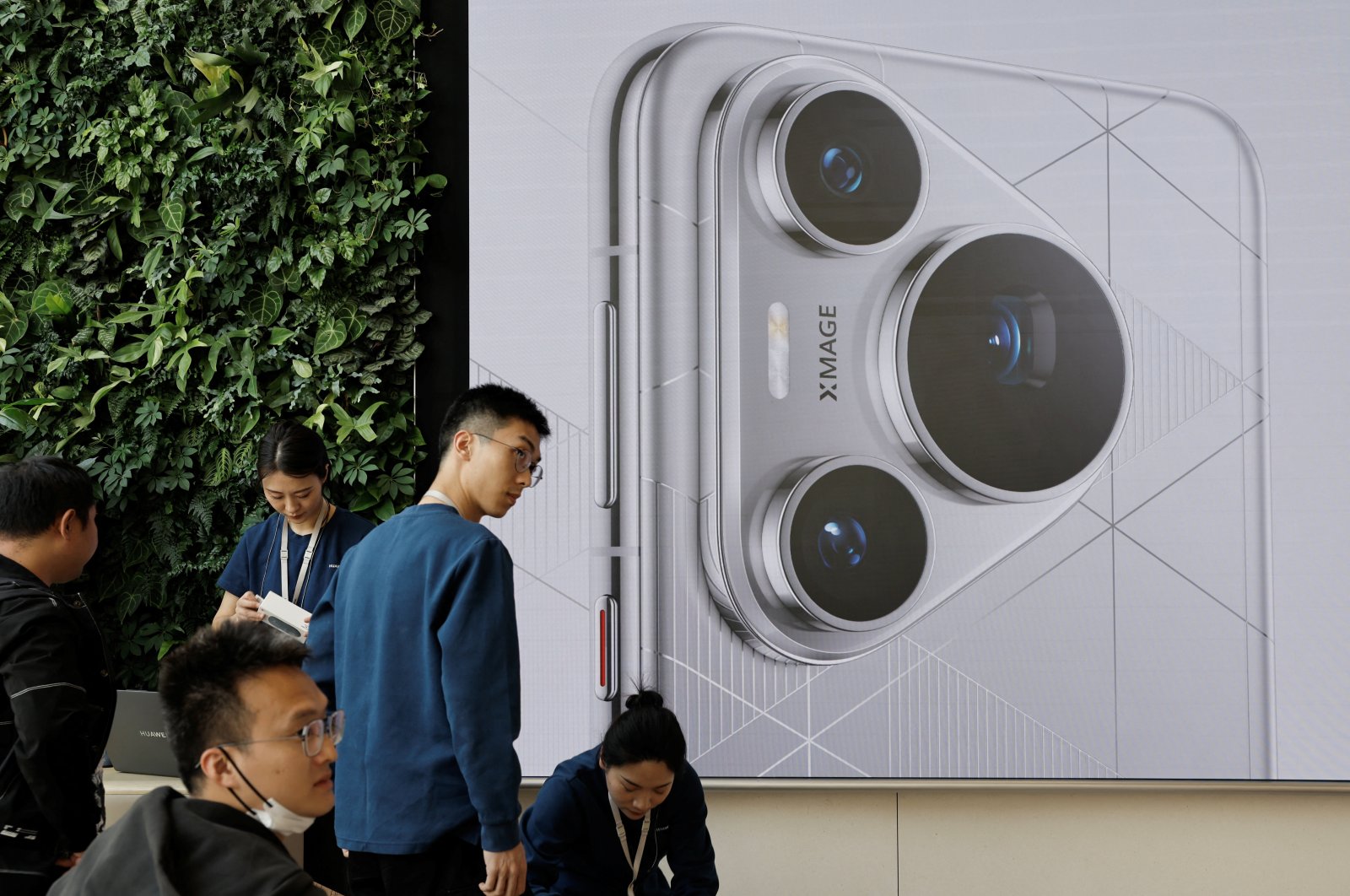 People stand near a screen showing the new Huawei Pura 70 series smartphone as the series models go on sale at Huawei&#039;s flagship store, Beijing, China, April 18, 2024. (Reuters Photo)