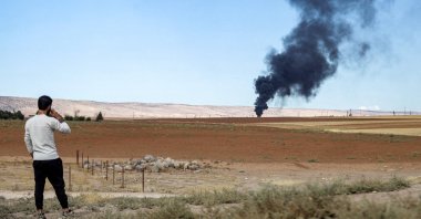 A man watches from afar as a fire rages after a Turkish airstrike at the Zarba oil facility occupied by the PKK/YPG terrorist group, al-Qahtaniyah, Syria, Oct. 5, 2023. (AFP Photo)
