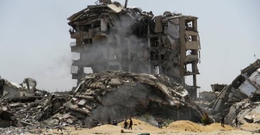 Palestinians walk past the rubble of residential buildings destroyed by Israeli strikes, northern Gaza Strip, Palestine, April 22, 2024. (Reuters Photo)