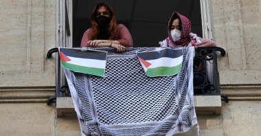 Student demonstrators look out of a window with a Palestinian keffiyeh and placards representing the Palestinian flag during the occupation of a building at Sciences Po, Paris, France, April 26, 2024. (AFP Photo)
