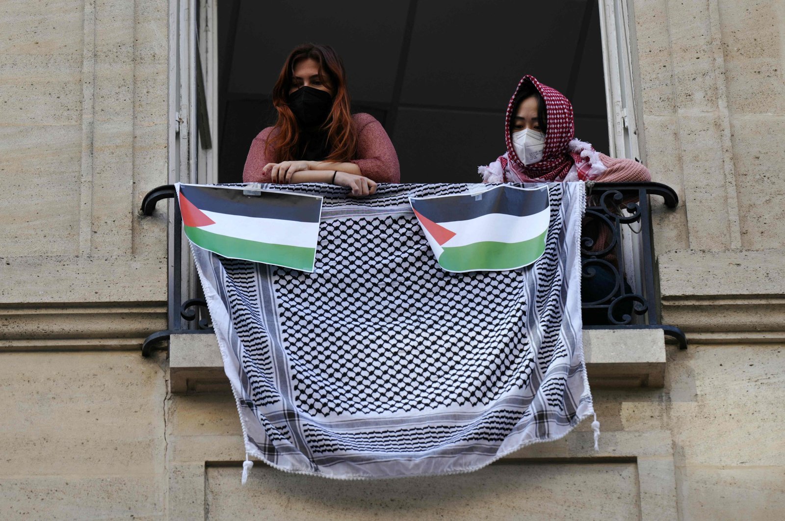 Student demonstrators look out of a window with a Palestinian keffiyeh and placards representing the Palestinian flag during the occupation of a building at Sciences Po, Paris, France, April 26, 2024. (AFP Photo)