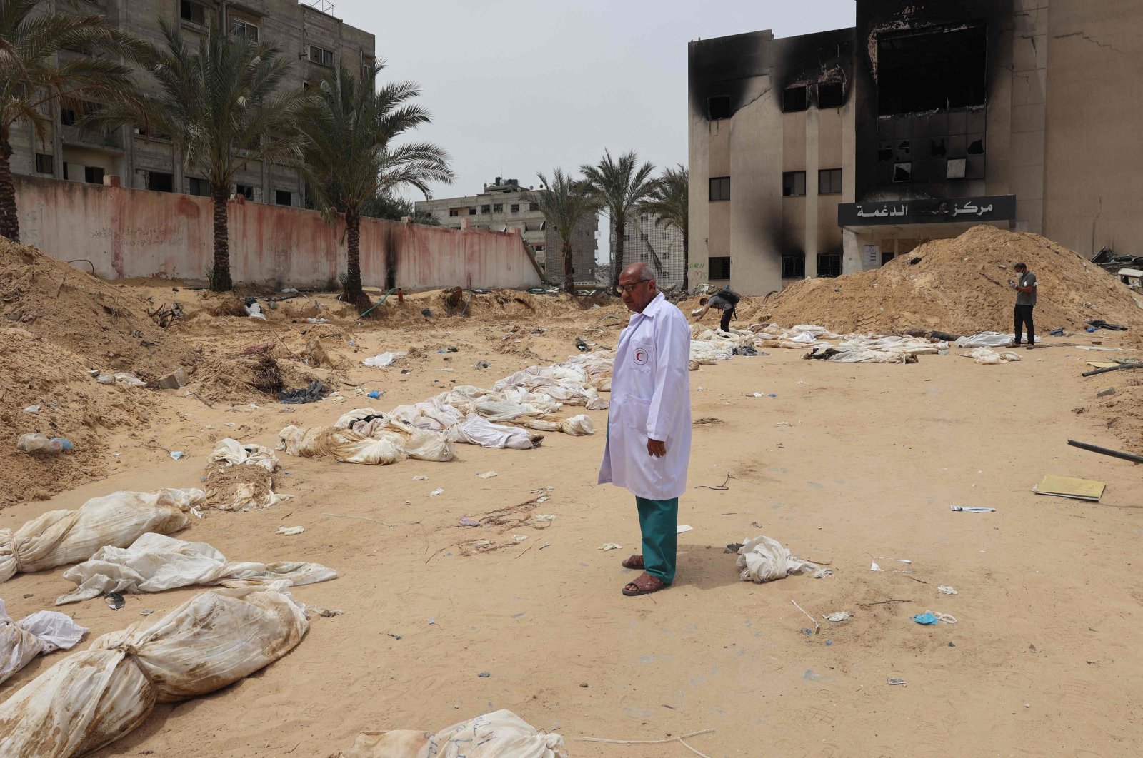 A doctor stands near bodies lined up for identification after they were unearthed from a mass grave found in the Nasser Medical Complex, southern Gaza Strip, Palestine, April 25, 2024. (AFP Photo)
