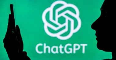 An image of a person holding a cell phone in front of a ChatGPT logo displayed on a computer screen, Edmonton, Canada, April 20, 2024. (Reuters Photo)