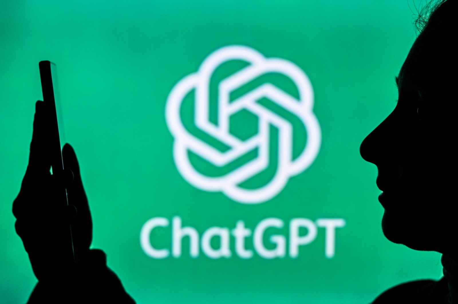 An image of a person holding a cell phone in front of a ChatGPT logo displayed on a computer screen, Edmonton, Canada, April 20, 2024. (Reuters Photo)