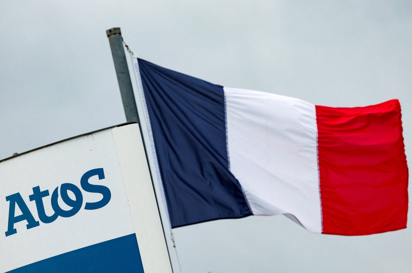 A French national flag flies near a logo of French IT consulting firm Atos, at the entrance of a company&#039;s building, Angers, France, March 20, 2024. (Reuters Photo)