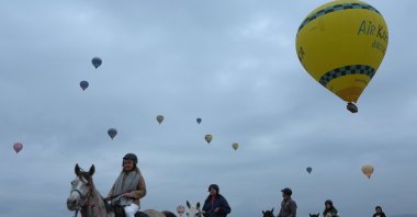 Tourists are photographed riding horses with the backdrop of hot air balloons in the popular tourist hot spot, Cappadocia, central Türkiye, April 14, 2024. (AA Photo)