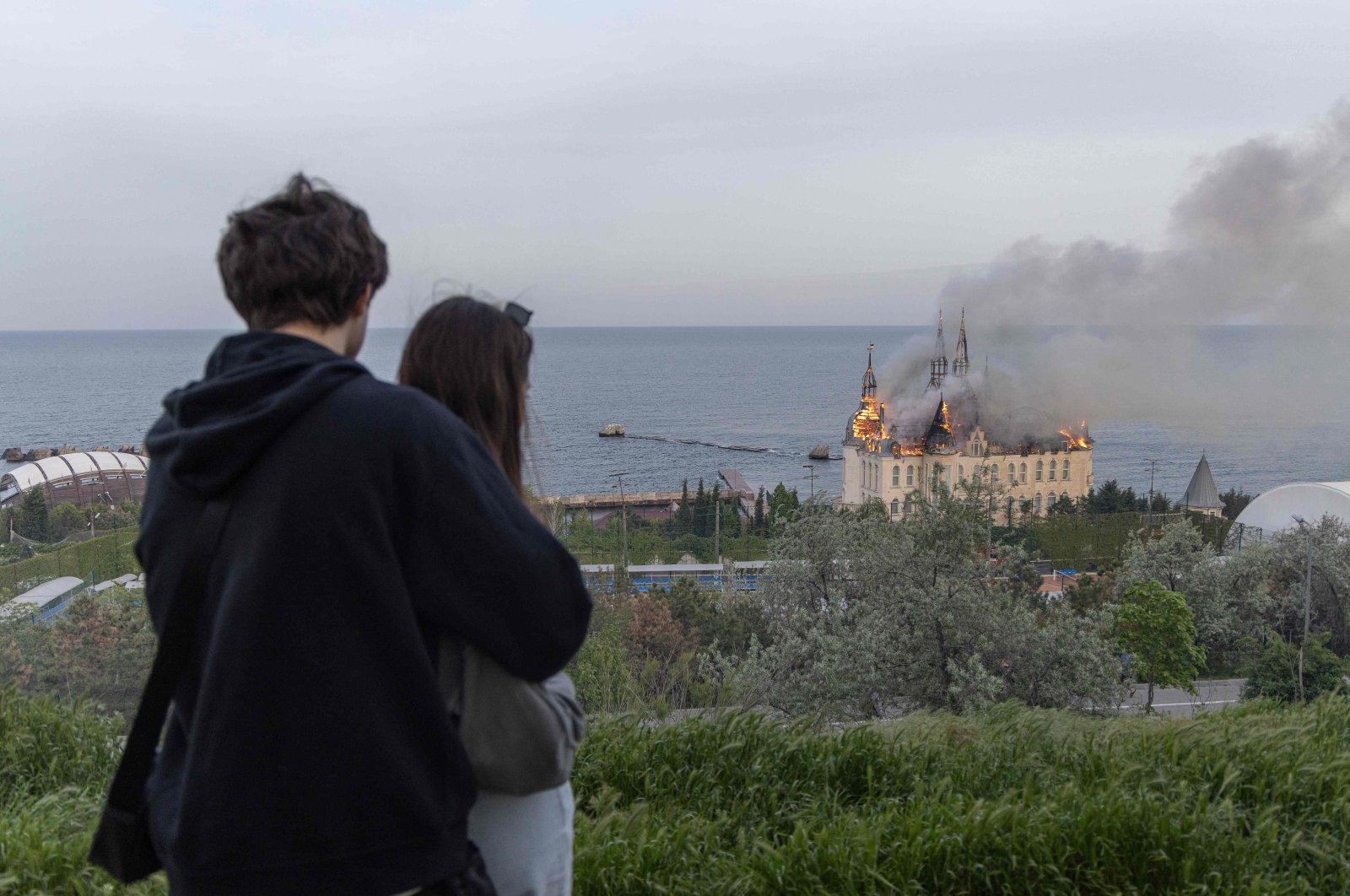 A couple looks toward a burning building damaged as a result of a missile attack in Odesa, Ukraine, April 29, 2024. (AFP Photo)