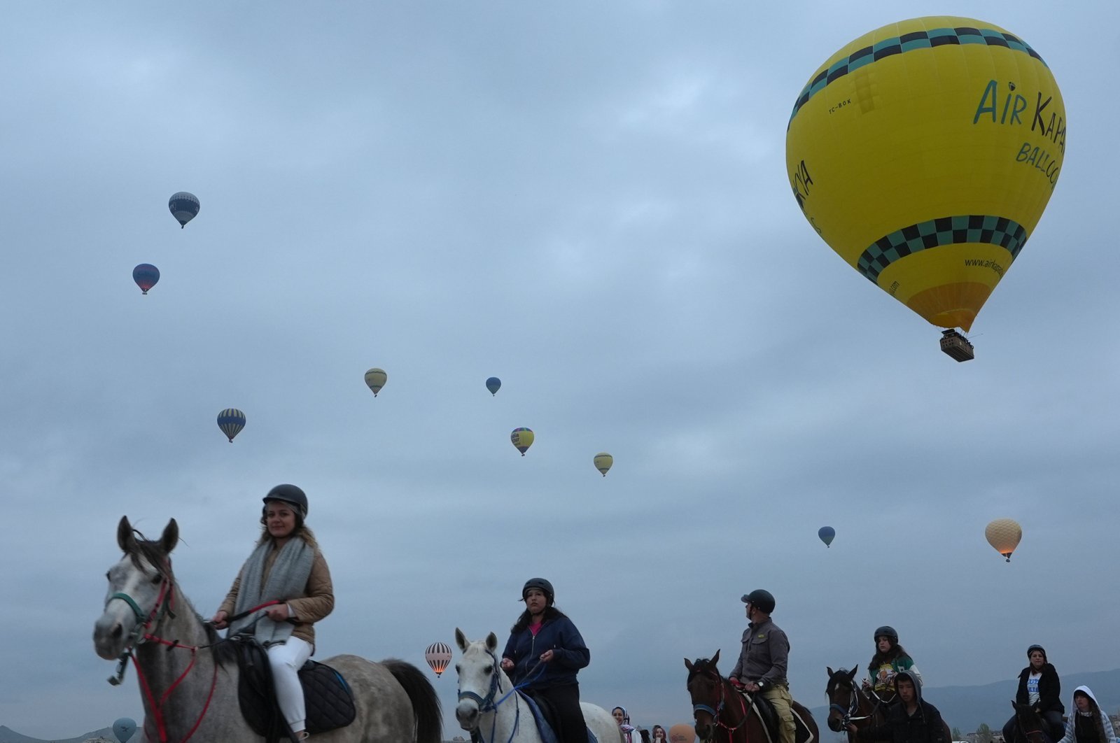 Tourists are photographed riding horses with the backdrop of hot air balloons in the popular tourist hot spot, Cappadocia, central Türkiye, April 14, 2024. (AA Photo)
