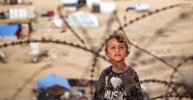 A child stands behind barbed-wire along a slope near a camp for displaced Palestinians in Rafah, southern Gaza Strip, Palestine, April 30, 2024. (AFP Photo)