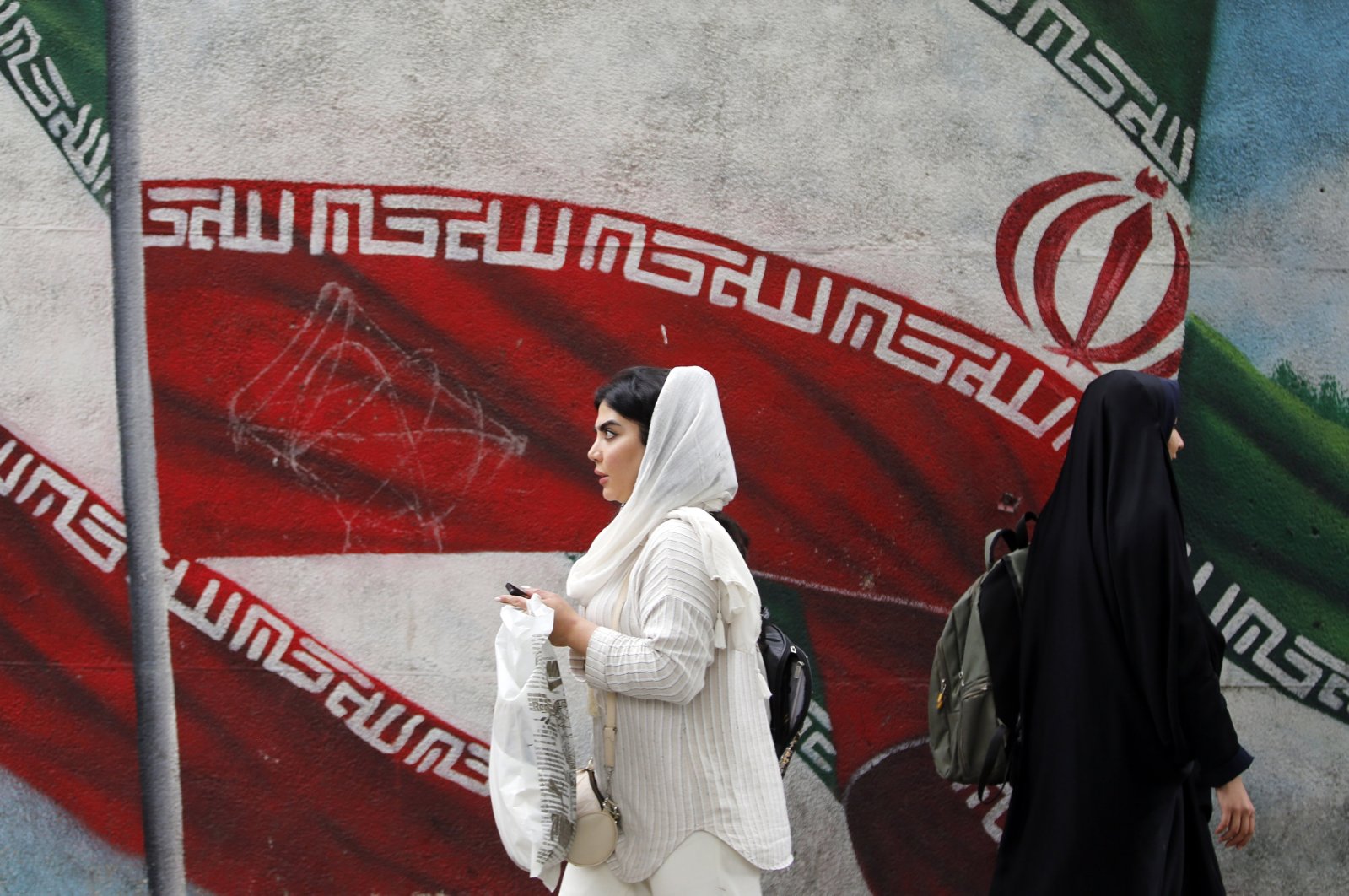 Iranian women walk past a painting of the national flag of Iran in Tehran, Iran, May 2, 2024. (EPA Photo)