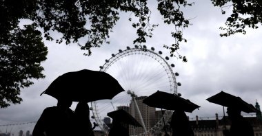 People walk on a rainy day near the London Eye Ferris wheel in London, Britain, May 4, 2024. (EPA Photo)