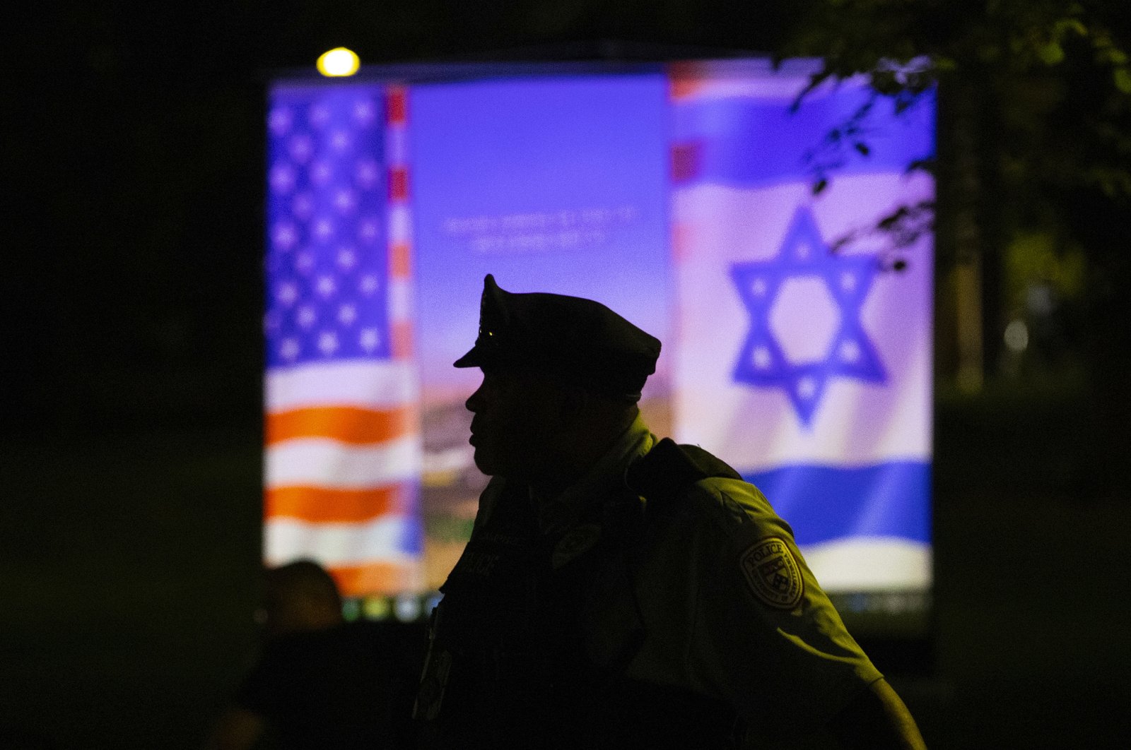 A Philadelphia police officer is silhouetted against a projected presentation on Hamas being shown by a pro-Israel group during a protest at Penn, in Philadelphia, U.S., May 2, 2024. (AP Photo)