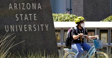 A cyclist crosses an intersection on the campus of Arizona State University, in Tempe, Arizona, Sept. 1, 2020. (AP Photo)