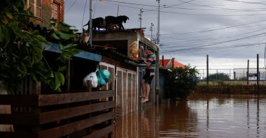 A man climbs a gate to access a house in a flooded area in Eldorado do Sul, Rio Grande do Sul state, Brazil, May 8, 2024. (Reuters Photo)