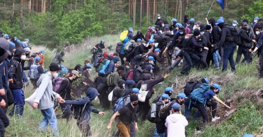 Activists run during a protest against the expansion of Tesla Gigafactory in Gruenheide near Berlin, Germany, May 10, 2024. (Reuters Photo)