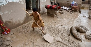 An Afghan boy shovels mud from the courtyard of a house following flash floods at a village in Baghlan-e-Markazi district of Baghlan province, Afghanistan, May 11, 2024.