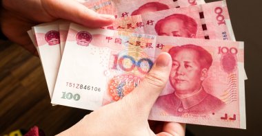 A person holds 100 RMB banknotes of China&#039;s yuan. (Shutterstock Photo)
