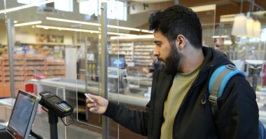 Jihad Ammuri, a 20-year-old Palestinian asylum-seeker, pays for his purchase with a special payment card in a grocery store, Eichsfeld, Germany, April 24, 2024. (AP Photo)