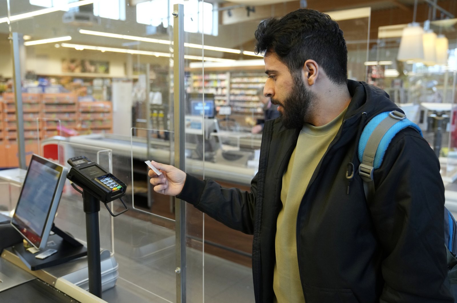 Jihad Ammuri, a 20-year-old Palestinian asylum-seeker, pays for his purchase with a special payment card in a grocery store, Eichsfeld, Germany, April 24, 2024. (AP Photo)