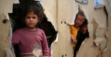 Internally displaced children peak out of holes in their classroom at a makeshift camp, in Idlib, Syria, May 11, 2024. (AFP Photo)