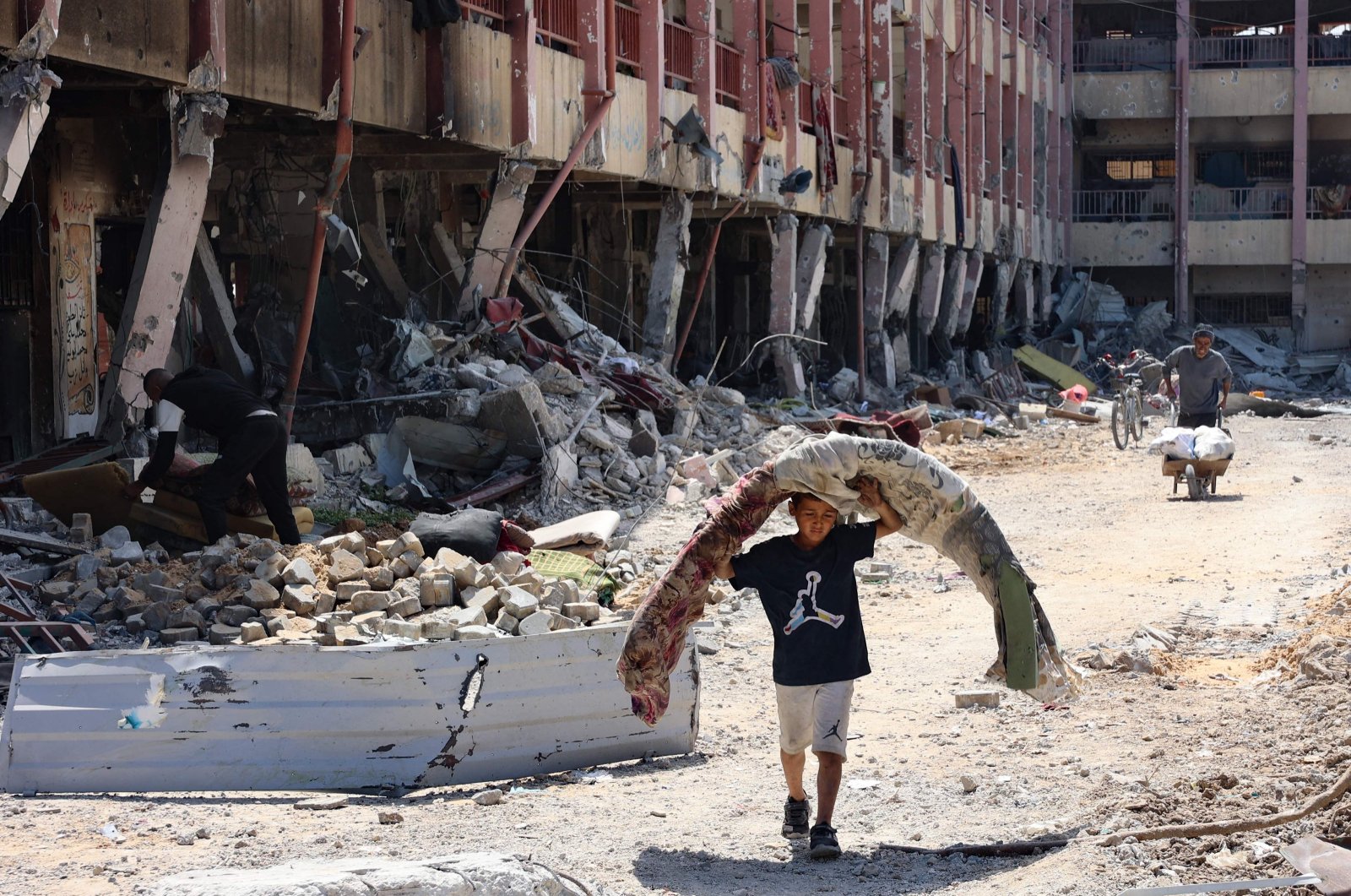 People walk in front of a devastated school building in the al-Zaitoun neighborhood of Gaza City in the northern part of the Palestinian territory, May 15, 2024. (AFP Photo)