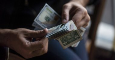 A person counts U.S. dollar banknotes. (Getty Images Photo)