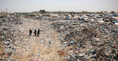 Children walk with bags of objects found in garbage piled up near tents set up by Palestinians displaced by Israeli attacks in Khan Younis in the southern Gaza Strip, May 18, 2024. (AFP Photo)