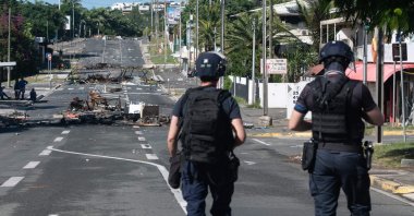 Police patrol a street blocked by debris and burnt-out items following overnight unrest in the Magenta district of Noumea, France's Pacific territory of New Caledonia, May 18, 2024. (AFP Photo)