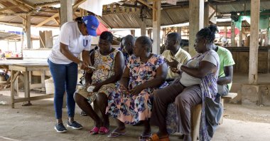Rita Quansah (L) from Uniti Networks, coaches farmers on how to navigate its platform of applications at a market in Hohoe, Ghana, April 18, 2024. (AP Photo)