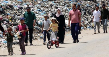 Displaced Palestinians walk past garbage piled up near tents in Khan Younis, in the southern Gaza Strip, Palestine, May 18, 2024. (AFP Photo)