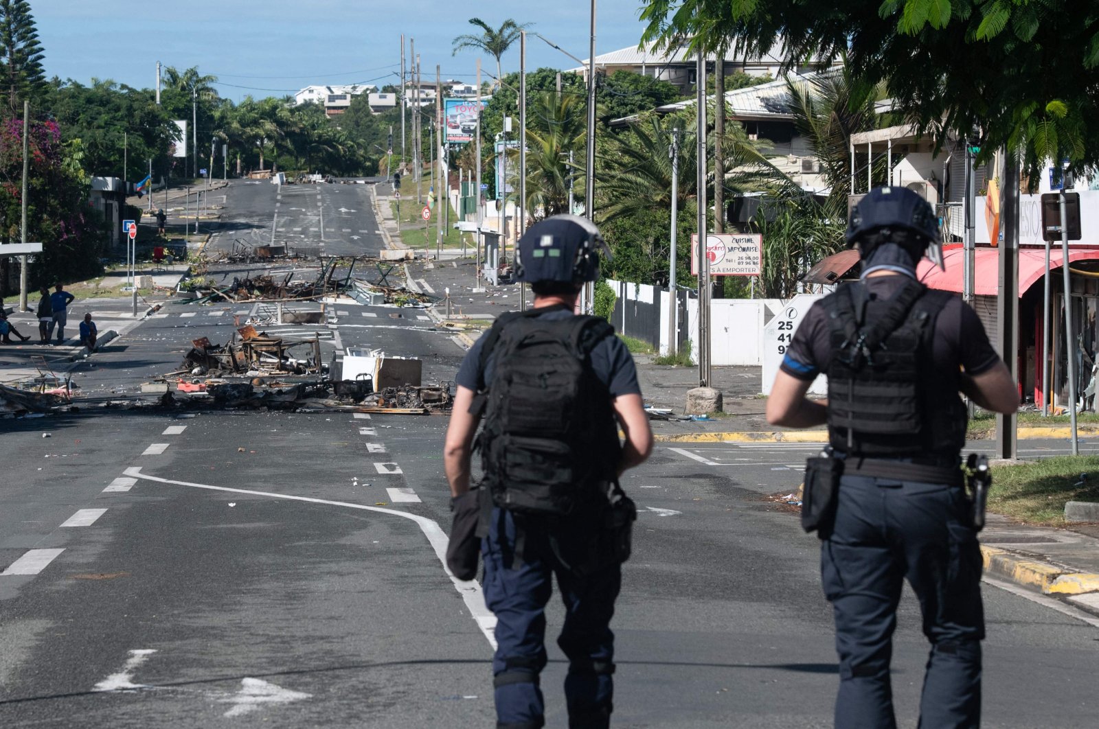 Police patrol a street blocked by debris and burnt-out items following overnight unrest in the Magenta district of Noumea, France&#039;s Pacific territory of New Caledonia, May 18, 2024. (AFP Photo)