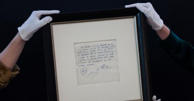 Members of staff show the napkin on which the 13-year-old Argentinian football player Lionel Messi was promised his first contract with FC Barcelona, during a photocall at Bonhams, London, U.K., May 8, 2024. (AFP Photo)